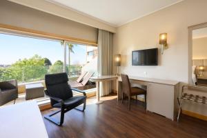 a hotel room with a desk and chairs and a large window at TRYP by Wyndham Porto Expo Hotel in Leça da Palmeira