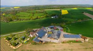 an aerial view of a house with solar panels on a field at Ferienwohnungen auf dem Erlenhof in Beverungen