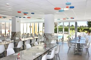 comedor con mesas y sillas y ventanas grandes en Bluewater Hotel, en Colonia de Sant Jordi