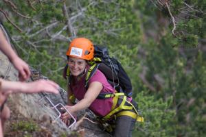 a woman in an orange helmet climbing up a mountain at HI Sjoa in Otta