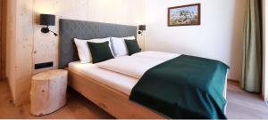 a bedroom with a bed with a green blanket on it at vomLandl Natur Lofts & Apartments Leogang in Leogang