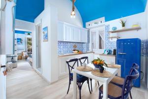 Il comprend une cuisine dotée de plafonds bleus ainsi que d'une table et de chaises blanches. dans l'établissement Estate4home - Blu Dream Massa, à Massa Lubrense