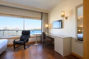 a hotel room with a desk and a bed and a window at TRYP by Wyndham Porto Expo Hotel in Leça da Palmeira