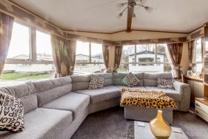a living room with a gray couch and windows at Lovely Caravan For Hire With Decking At Skipsea Sands In Yorkshire Ref 41015wf in Barmston