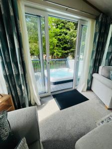 un salon avec un canapé et une porte coulissante en verre dans l'établissement Coopers Corner, Lodge with Hot Tub, à York