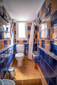 a blue tiled bathroom with a toilet and a window at Villa Mavrianos Sea View in Kithnos