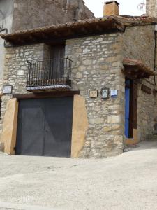 a stone building with a black garage door at Casa La Cantonera con zona relax jacuzzi in La Cuba