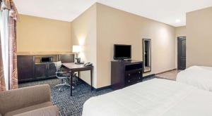 a hotel room with a bed and a desk with a television at La Quinta by Wyndham McAlester in McAlester