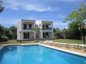 a villa with a swimming pool in front of a house at Apartamentos Marivent in Cala en Blanes