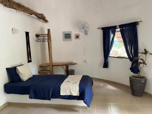 1 dormitorio con cama con sábanas azules y ventana en Footsteps Eco-Lodge, en Gunjur