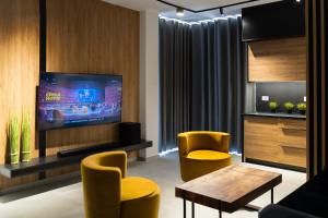 a living room with a tv and yellow chairs at Santa Quaranta Apartment 1 in Sarandë