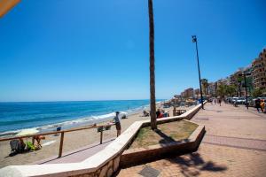 a beach with people sitting on the sand and the ocean at Yate 4, primera linea de playa. in Fuengirola