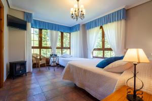 ein Schlafzimmer mit einem Bett und zwei Fenstern in der Unterkunft Posada El Trasmerano in Argoños