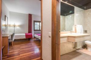a bathroom with a sink and a toilet and a bed at Snö Hotel Formigal in Formigal