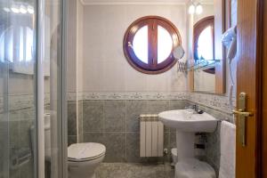 a bathroom with a toilet and a sink and a mirror at Posada El Trasmerano in Argoños