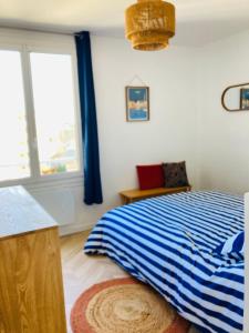 a bedroom with a blue and white bed and a window at Rêve Salé Appartement Vue Mer 2 à 4 pers in Dieppe
