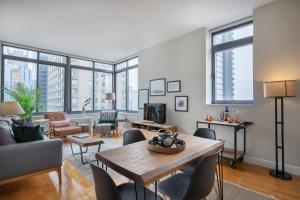 un salon avec une table, des chaises et des fenêtres dans l'établissement Modern Bright Times Sq 1BR w Indoor pool NYC-8, à New York