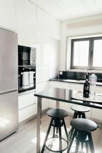 a white kitchen with a table and two stools at Vale Do Mar House in Espinho