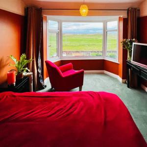 ein Schlafzimmer mit einem roten Bett, einem Stuhl und einem Fenster in der Unterkunft Liverpool - Cosy Jazzy Beach Home! in Waterloo