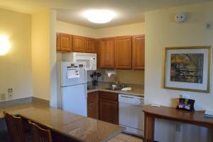 a kitchen with a white refrigerator and wooden cabinets at Staybridge Suites Houston West - Energy Corridor, an IHG Hotel in Houston