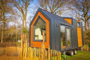 een oranje en zwart tiny house op een trailer bij Vakantiepark Sallandshoeve in Nieuw-Heeten