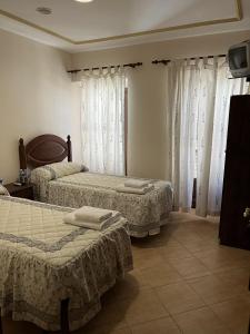 a bedroom with two beds and curtains and a tv at El Carmen in Benalúa de Guadix
