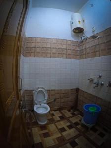 a bathroom with a toilet in a tiled room at Gaharwar Home Stay in Dehradun