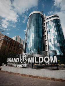 a building with the grand millionord sign in front of it at Grand Mildom Hotel in Almaty