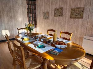 uma mesa de jantar em madeira com cadeiras e comida em Par les Prés et les Bois de Sologne 