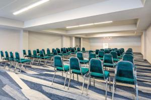 Comfort Inn & Suites في باري: قاعة اجتماعات فارغة فيها كراسي خضراء