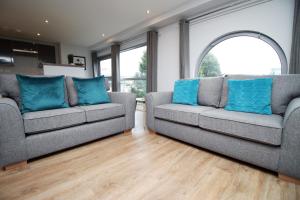 two gray couches in a living room with blue pillows at Violets Corner Luxury Swindon Town Apartment Great Location In The South West in Swindon