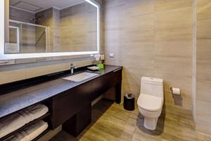 a bathroom with a sink and a toilet and a mirror at La Quinta by Wyndham Santiago Aeropuerto in Santiago