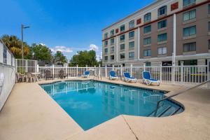 a swimming pool in front of a hotel with chairs and a building at Quality Inn & Suites in Myrtle Beach