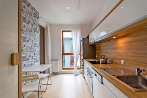 a kitchen with a sink and a counter with a table at Nadmorski Dwór by Grand Apartments in Gdańsk