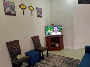 a living room with a tv and two chairs at Syah Homestay in Dungun