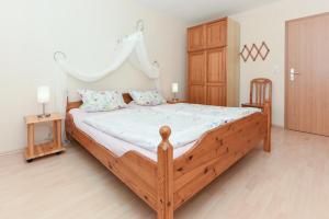 a bedroom with a wooden bed with white sheets at Ferienhof Gerdes in Holtgast