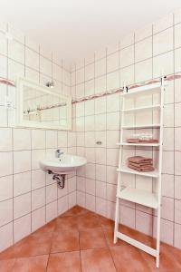 a white bathroom with a sink and a shelf at Ferienhof Gerdes in Holtgast