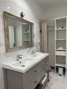 uma casa de banho branca com um lavatório e um espelho em Maison Riquet em Castelnaudary