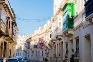 Una hilera de edificios en una calle con coches aparcados. en Enjoy and Relax at the Blu House, en Sliema