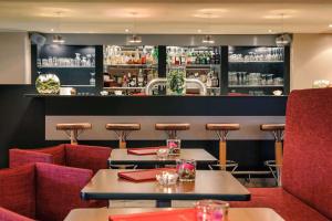 a restaurant with tables and chairs and a bar at Vienna House Easy by Wyndham Frankfurt Airport in Kelsterbach