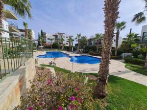 um resort com uma piscina e uma palmeira em DANAOS 2 COMPLEX APARTMENT - By IMH Travel & Tours em Pafos