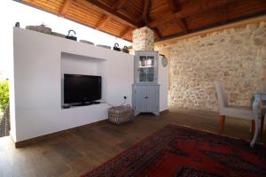sala de estar con TV de pantalla plana en la pared en Authentic Stone House with an outdoor living room en Jezera