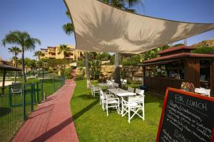 un ristorante con tavoli e sedie bianchi sull'erba di Quartiers Marbella Golden Penthouse a Benahavís