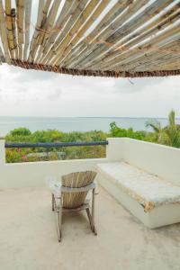 a chair and a bed on a balcony with the ocean at The Slow Leopard Kilwa in Kilwa Masoko
