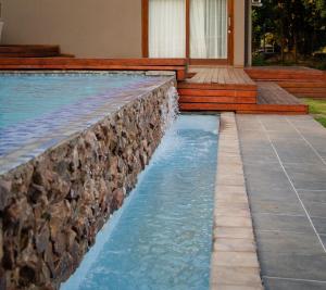 Una piscina con un muro de contención de piedra y una casa. en Elim Lakeside House, en Elim 15 fotos más