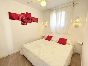 Un dormitorio con una cama con almohadas rojas. en Apartamentos Formentera Cordula 5, en Es Pujols