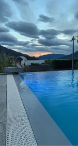 a blue swimming pool with a sunset in the background at Hotel Domaso in Domaso
