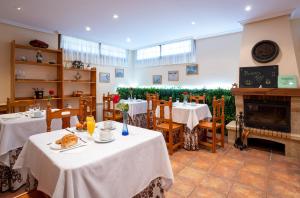 a dining room with two tables and a fireplace at Posada El Trasmerano in Argoños