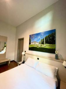 a bedroom with a white bed with a painting on the wall at Best Quality Hotel Dock Milano in Turin