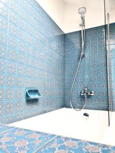 y baño con ducha de azulejos azules. en Les Quartiers d'Annelise, en Verdún